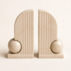 Pair of beige marble bookends with rounded arch design and decorative sphere detail.