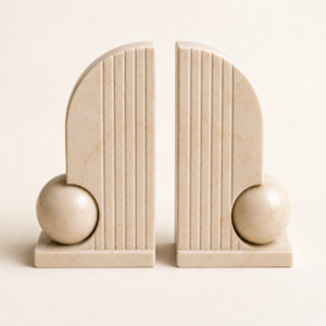 Pair of beige marble bookends with rounded arch design and decorative sphere detail.