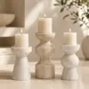 Three luxury marble candle holders with cream pillar candles on a neutral background.