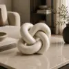 Luxury beige marble knot sculpture with polished natural veining on a neutral marble surface.