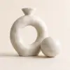 Beige natural marble knot sculpture with matching marble sphere on a neutral background.