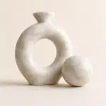 Beige natural marble knot sculpture with matching marble sphere on a neutral background.