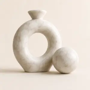 Beige natural marble knot sculpture with matching marble sphere on a neutral background.