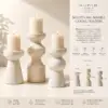 Sculptural marble candle holders with lit candles displayed in a luxury interior setting.