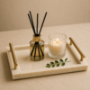 Luxury cream marble tray with brass handles styled with candle and diffuser on a coffee table.