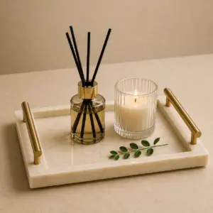 Luxury cream marble tray with brass handles styled with candle and diffuser on a coffee table.
